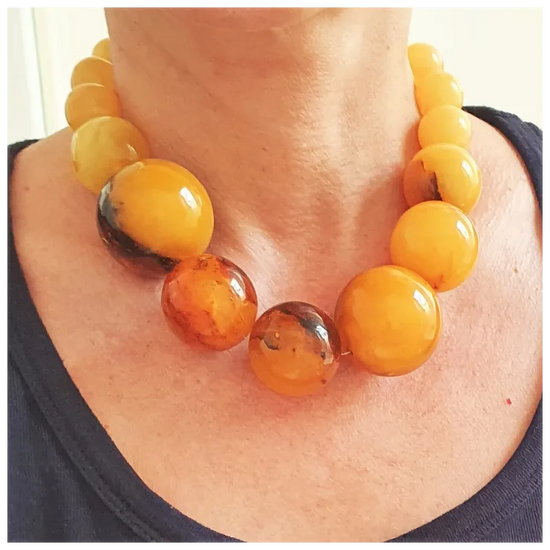 Close-up of a person wearing a necklace with large amber beads.
