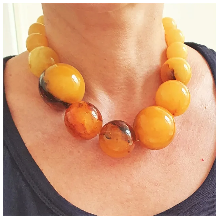 Close-up of a person wearing a necklace with large amber beads.