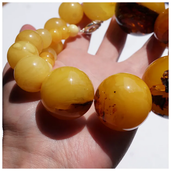 Close-up of amber beaded bracelet on a hand with a white background