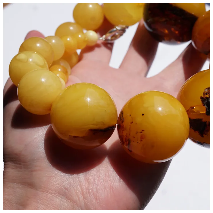 Close-up of amber beaded bracelet on a hand with a white background