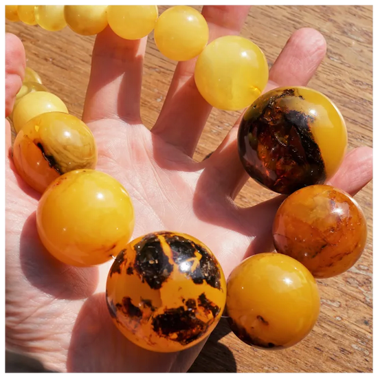 Hand holding a bracelet with amber beads on a wooden surface