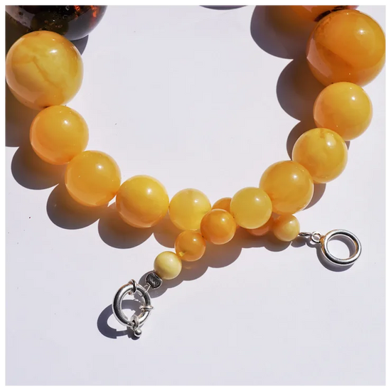 Yellow beaded bracelet with a silver clasp on a white background
