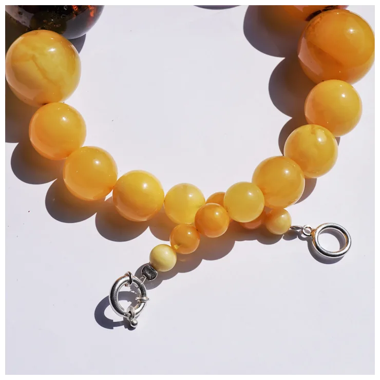 Yellow beaded bracelet with a silver clasp on a white background