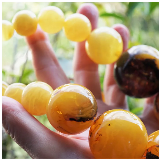Close-up of amber beads held by a hand with a blurred natural background