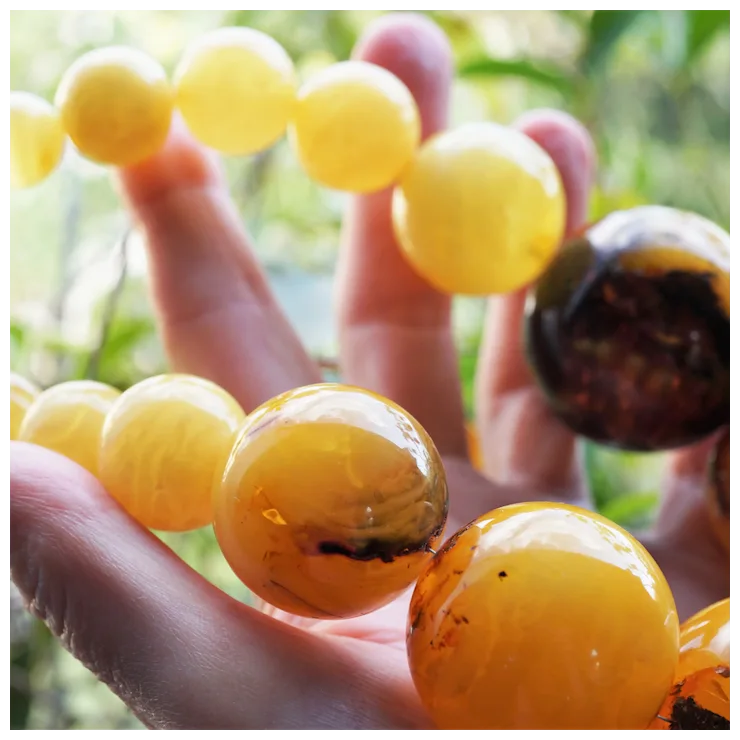 Close-up of amber beads held by a hand with a blurred natural background
