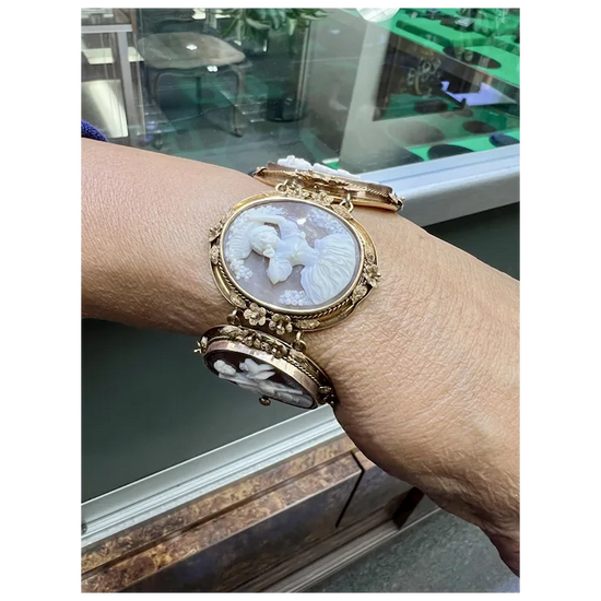 Gold wristwatch with intricate design worn on a wrist, blurred background