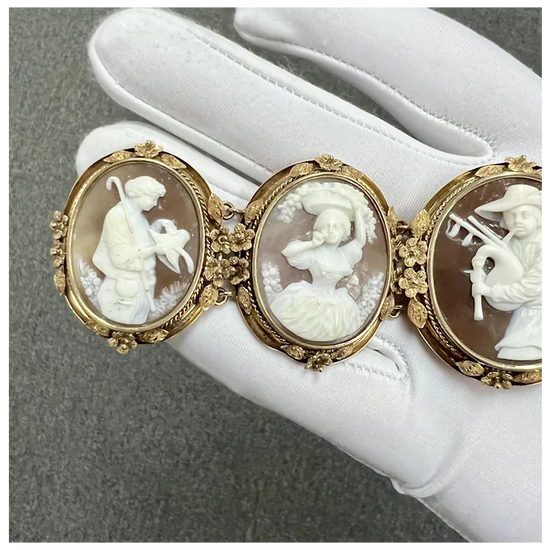 Three ornate cameos on a white surface with a gray background