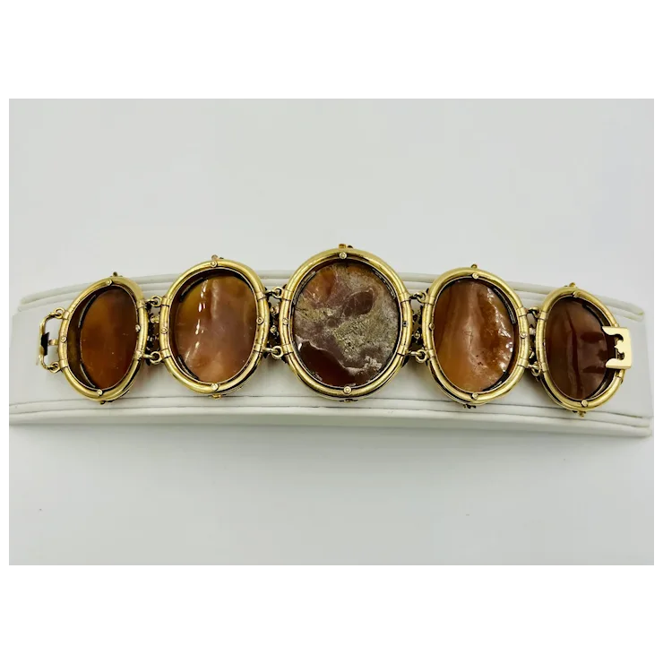 Gold bracelet with five brown oval stones on a white background