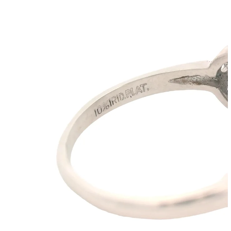 Close-up of a silver ring with '10K W.R.D. PLAT.' engraving on a white background
