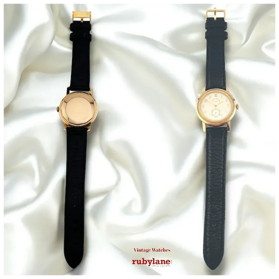 Two vintage watches with black straps on a white fabric background, featuring the Rubylane brand.
