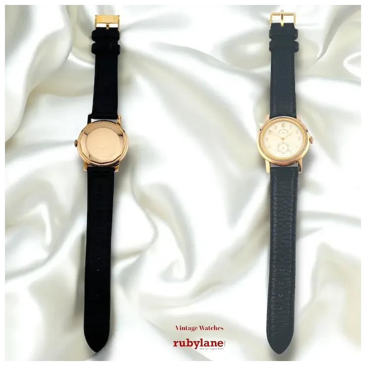 Two vintage watches with black straps on a white fabric background, featuring the Rubylane brand.