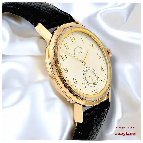 Gold wristwatch with black strap on a white fabric background, featuring Rubylane branding.