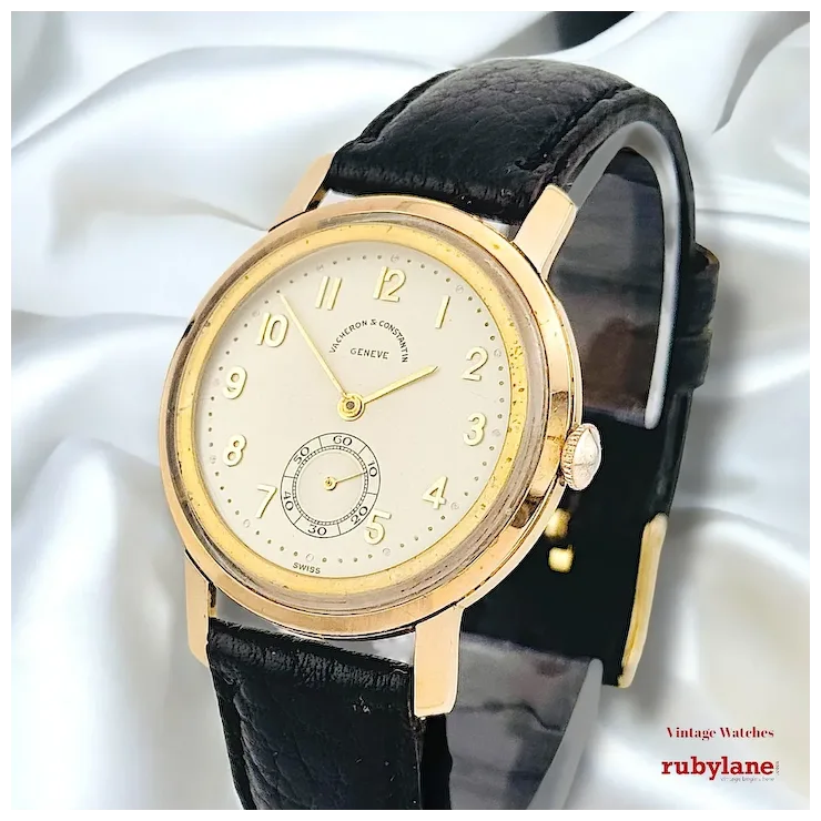 Vintage watch with black leather strap and gold case on a white background, featuring Rubylane branding.