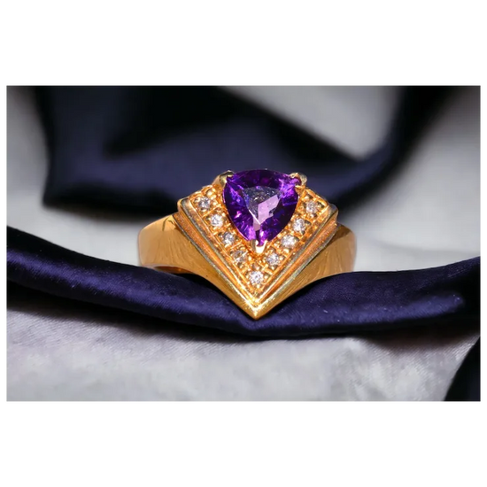 Gold ring with a purple gemstone on a dark fabric background