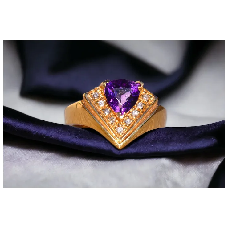 Gold ring with a purple gemstone on a dark fabric background