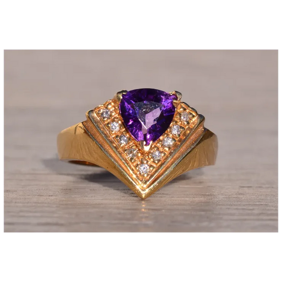 Gold ring with a purple gemstone on a wooden surface