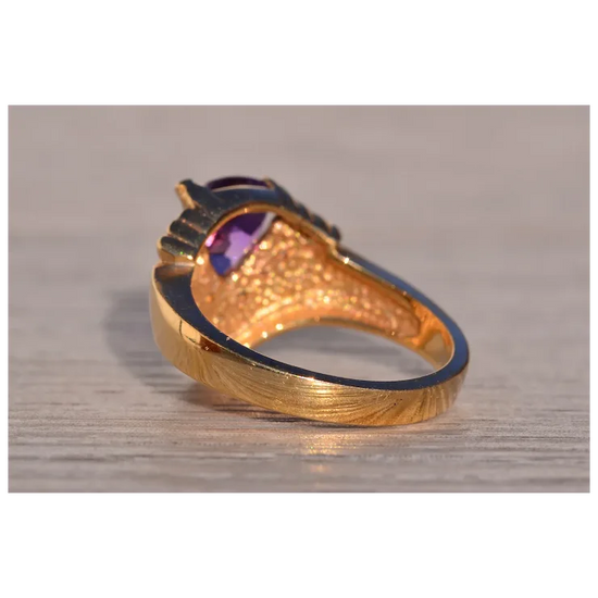 Gold ring with a purple gemstone on a wooden surface