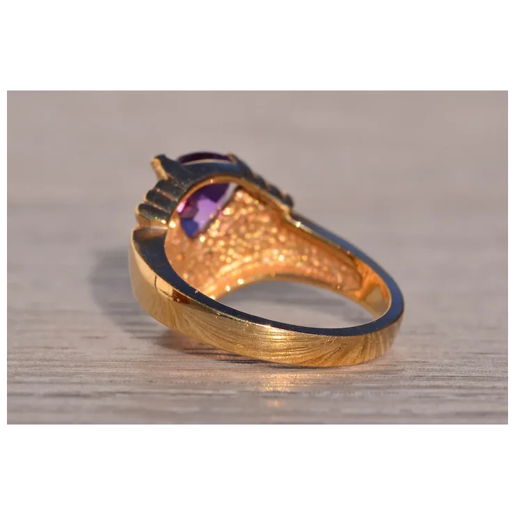 Gold ring with a purple gemstone on a wooden surface