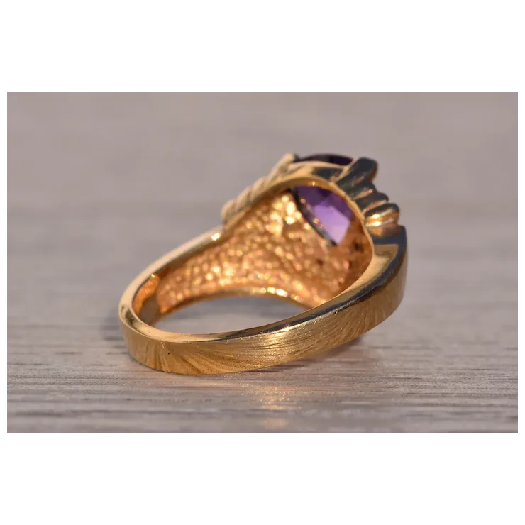 Gold ring with a purple gemstone on a wooden surface