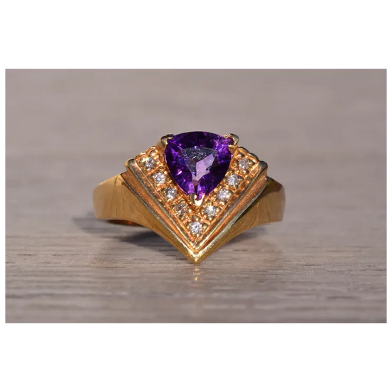 Gold ring with a purple gemstone on a wooden surface