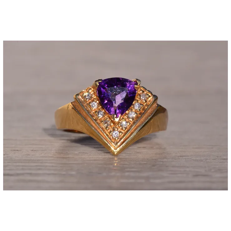 Gold ring with a purple gemstone on a wooden surface