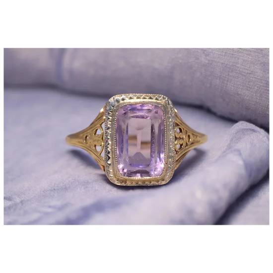 Gold ring with a purple gemstone on a soft fabric background