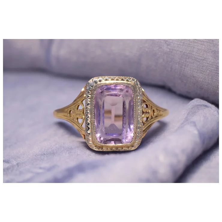 Gold ring with a purple gemstone on a soft fabric background