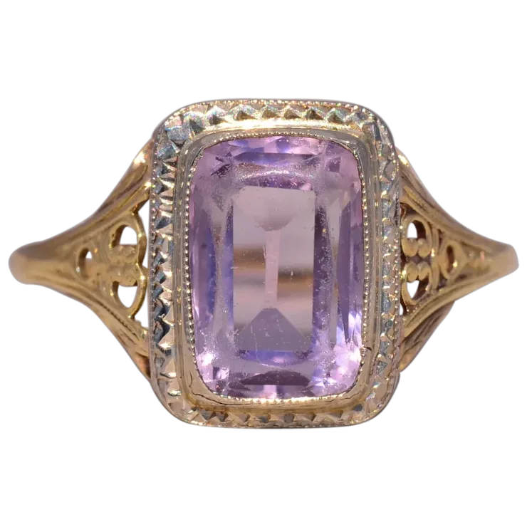 Gold ring with a purple gemstone on a white background