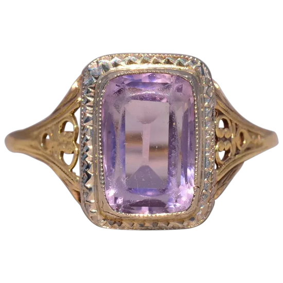 Gold ring with a purple gemstone on a white background