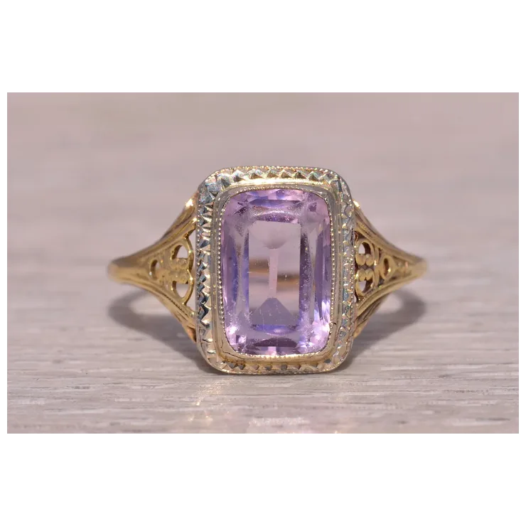Gold ring with a purple gemstone on a light wooden surface