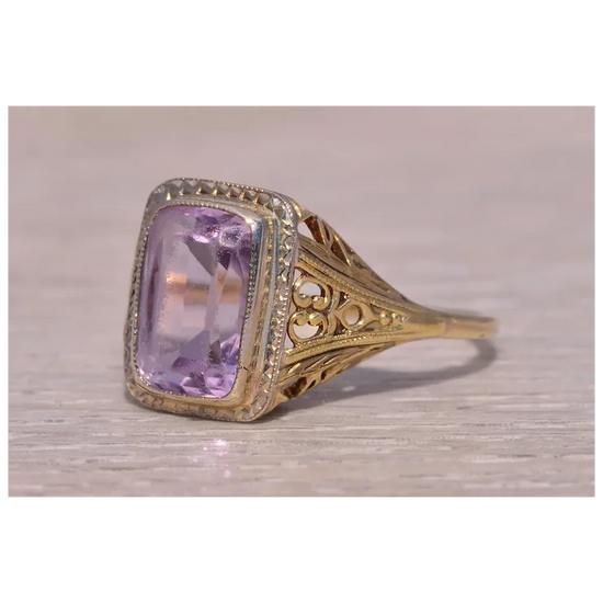 Gold ring with a purple gemstone on a wooden surface