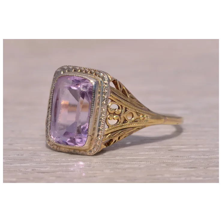 Gold ring with a purple gemstone on a wooden surface