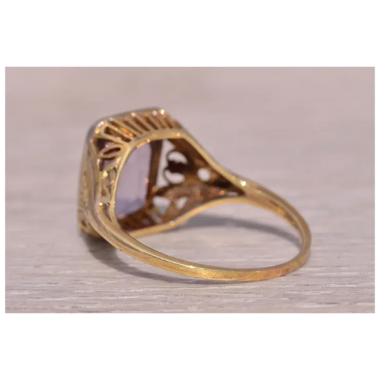Gold ring with intricate design on a light wooden surface