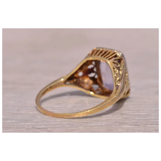 Gold ring with a clear gemstone on a light wooden surface