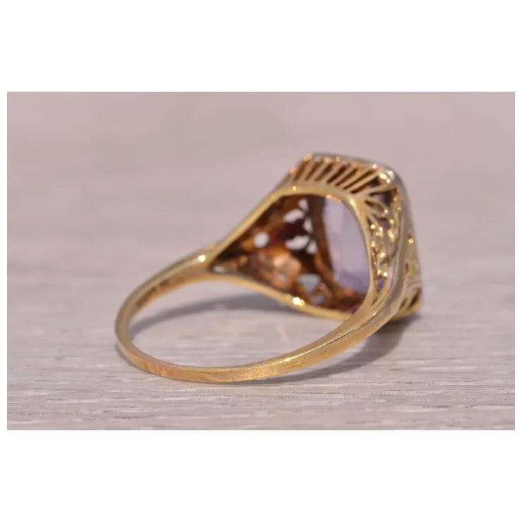 Gold ring with a clear gemstone on a light wooden surface