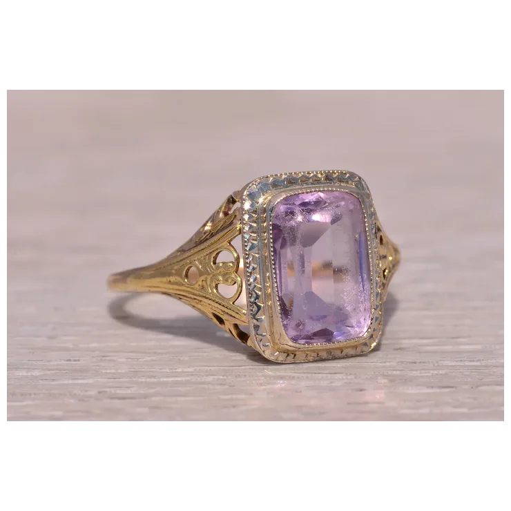 Gold ring with a purple gemstone on a light wooden surface