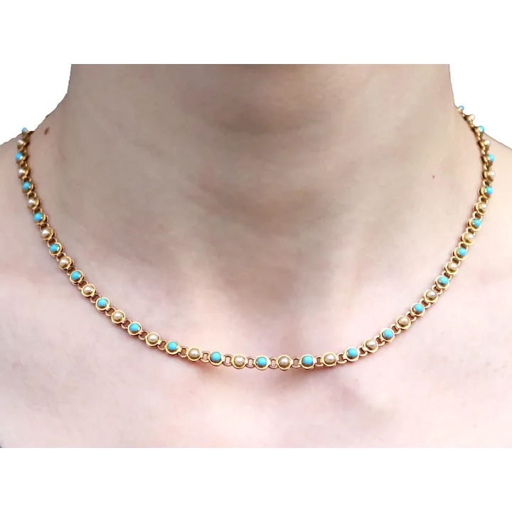 Gold necklace with turquoise stones on a plain background