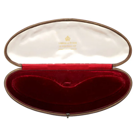 Oval jewelry box with red interior and gold exterior, featuring a brand logo.