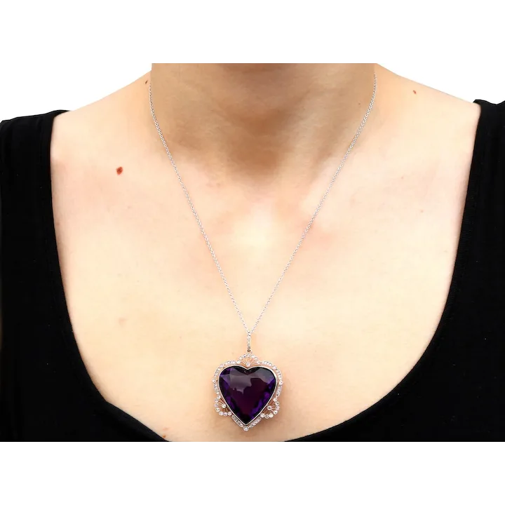Person wearing a necklace with a purple heart pendant on a plain background