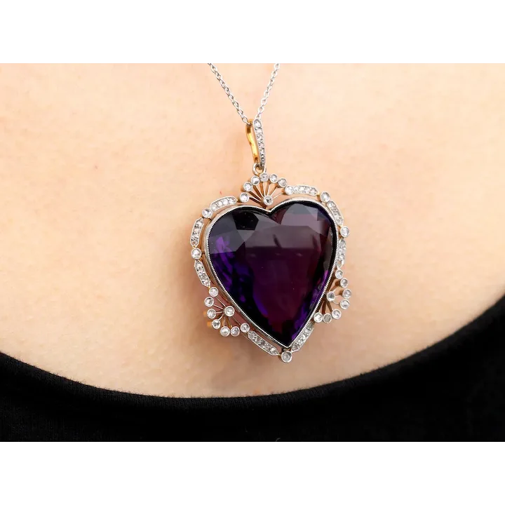 Heart-shaped purple gemstone pendant on a necklace against a plain background