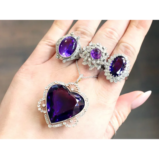Purple gemstone jewelry set held in a hand with a blurred background