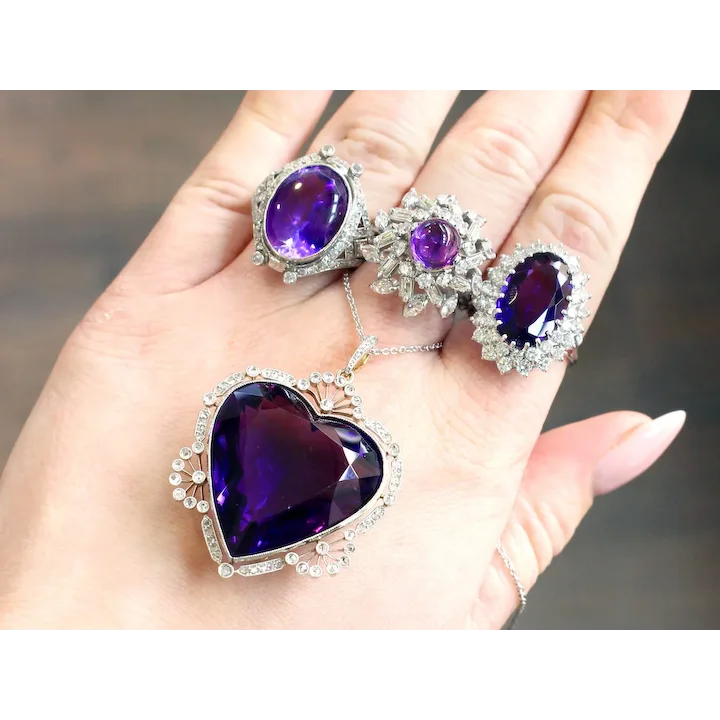 Purple gemstone jewelry set held in a hand with a blurred background
