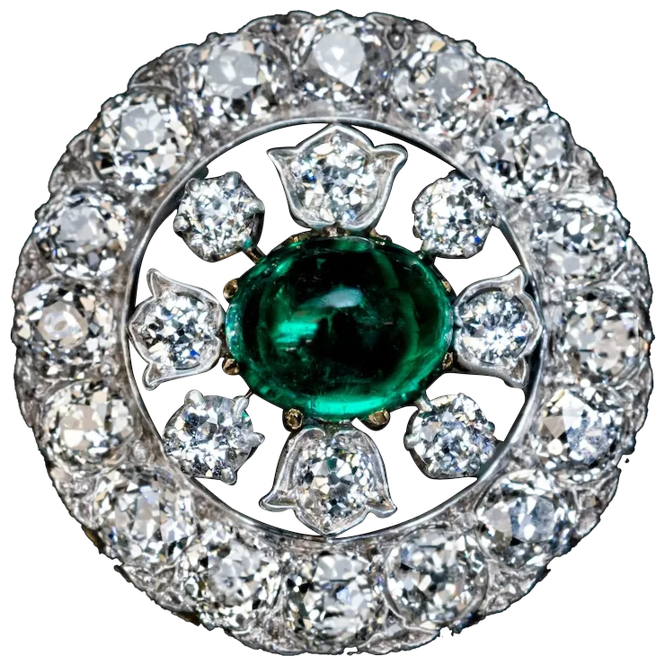 Diamond ring with a central emerald stone on a white background