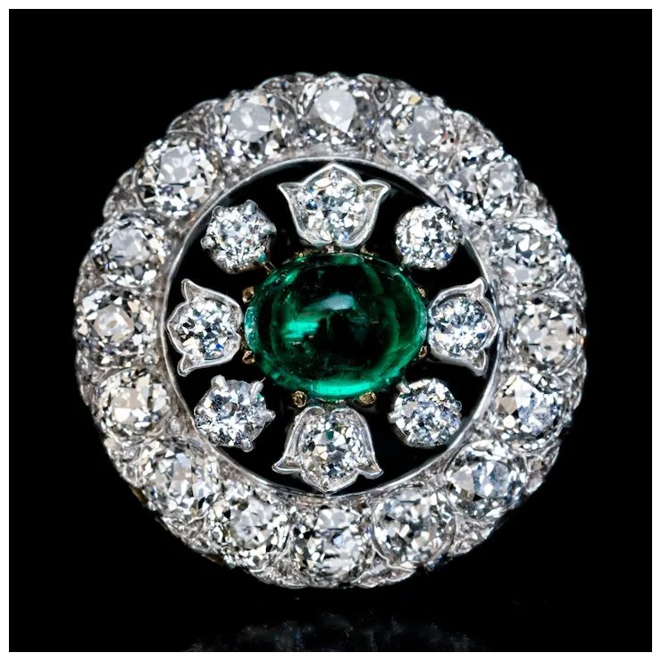 Jewelry item with a green gemstone surrounded by diamonds on a black background