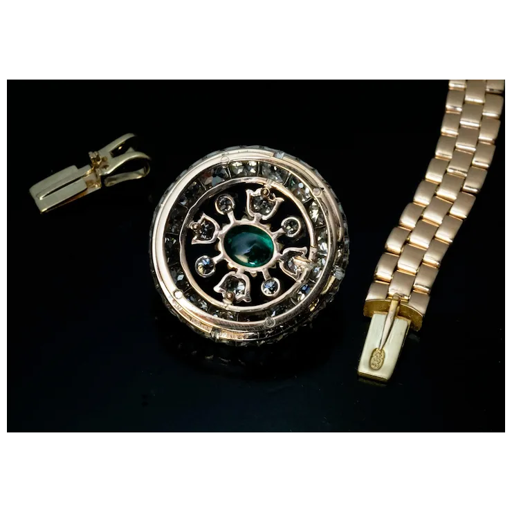 Gold locket with green gemstone and gold bracelet on a black background