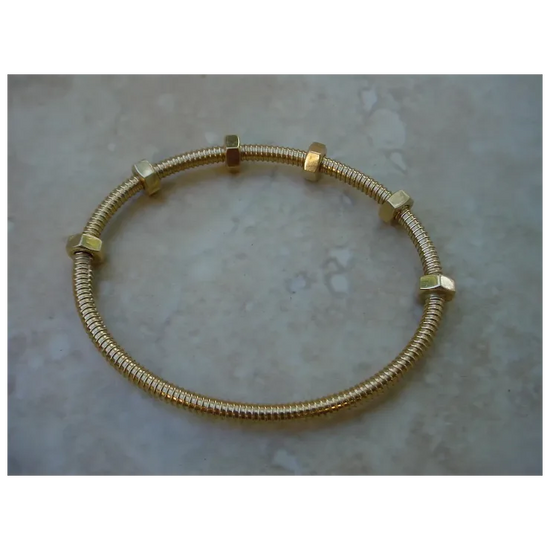 Gold bracelet with hexagonal links on a textured surface