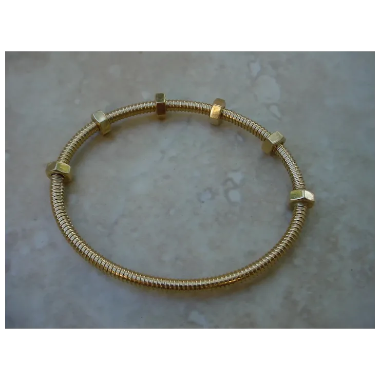 Gold bracelet with hexagonal links on a textured surface