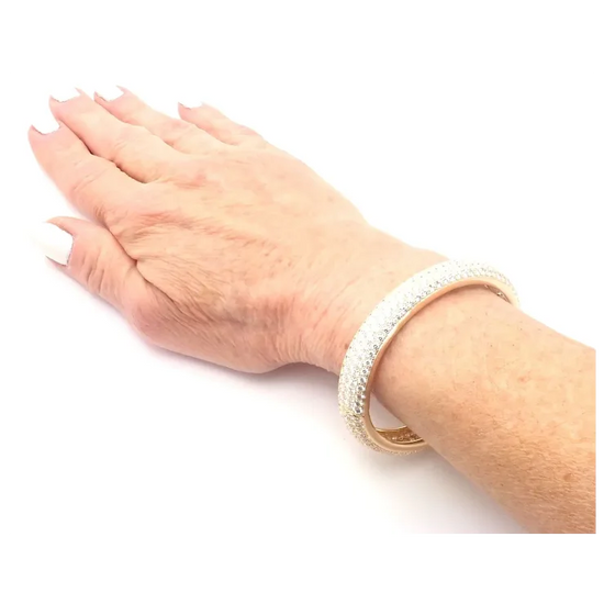Hand wearing a gold bracelet on a white background