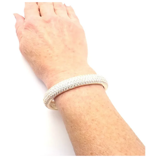 Silver bracelet on a wrist against a white background