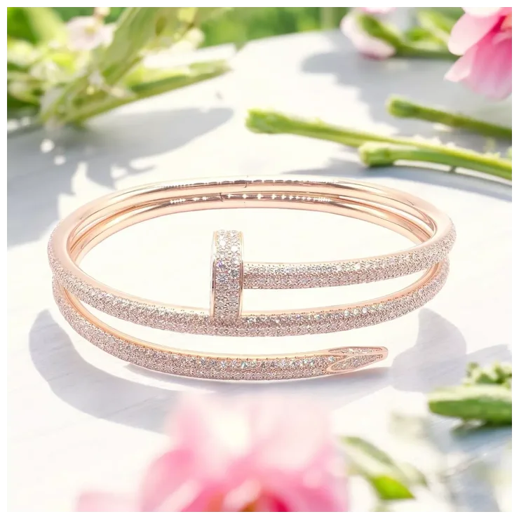 Rose gold bracelet on a white surface with blurred flowers in the background
